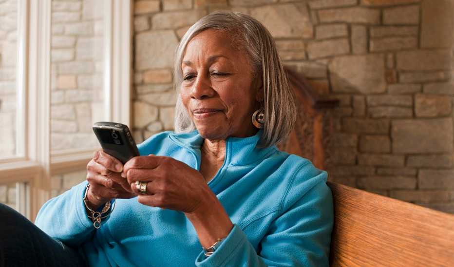 A woman sitting as she looks at and uses her cell phone