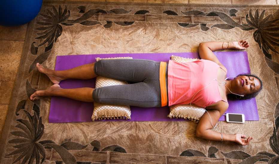 An overhead view of a woman lying on her back meditating