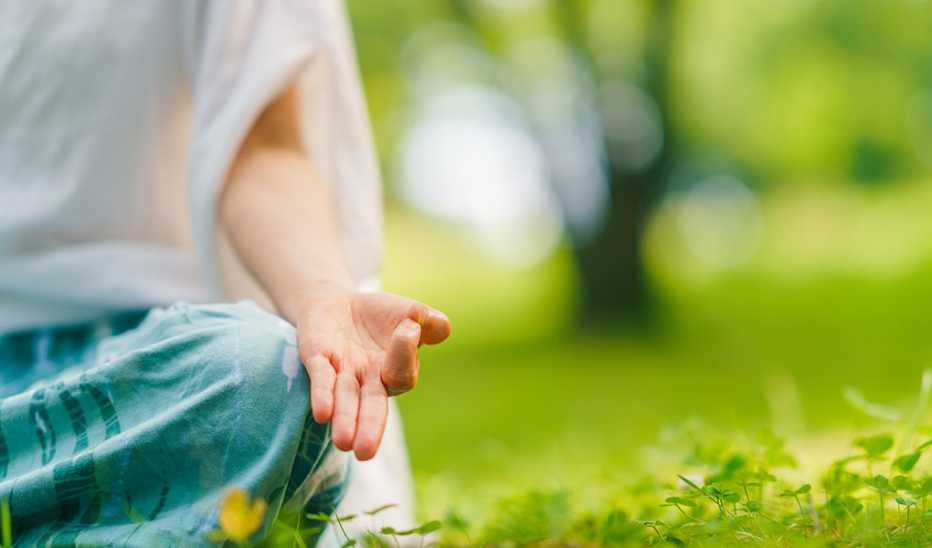 A close-up view of a woman's hand while in a yoga position in nature