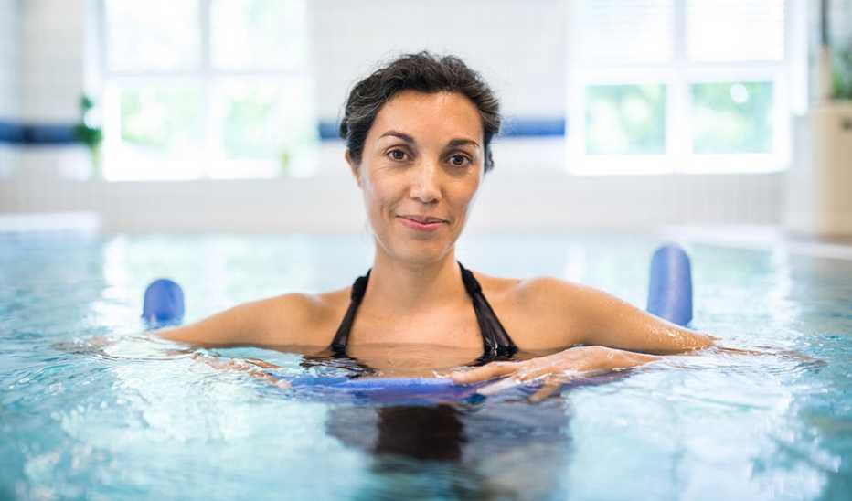 A woman in an indoor pool with a noodle float