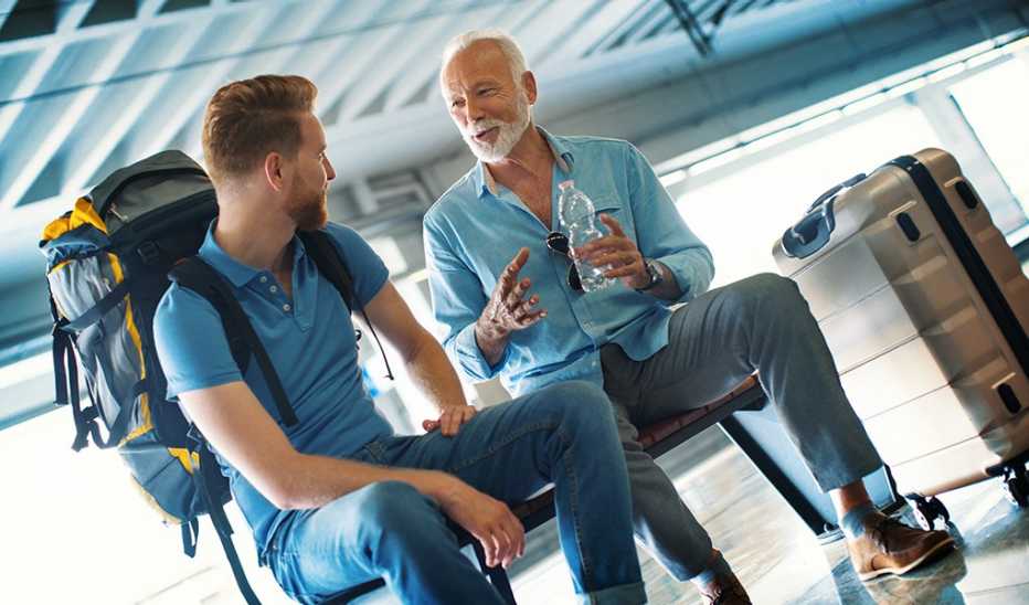 Two men, one younger, making small talk in a train station