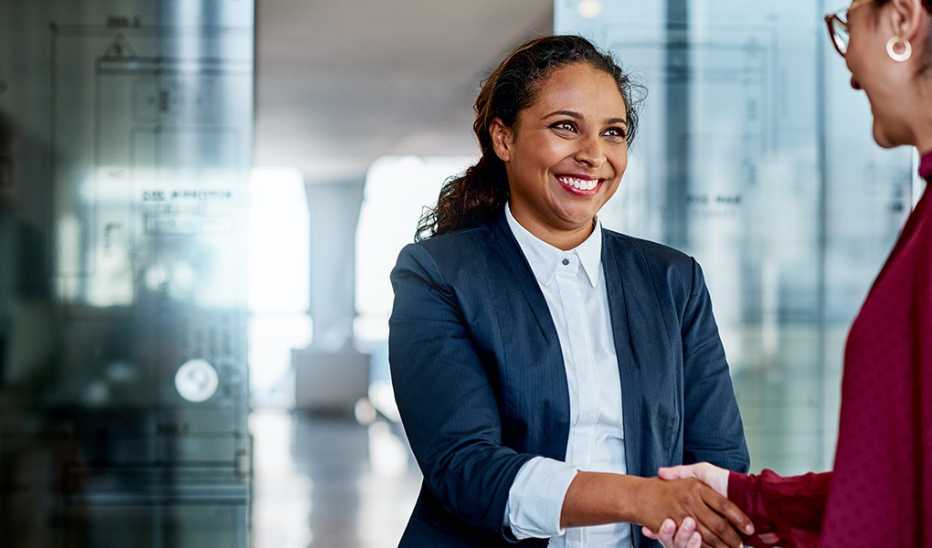 Two businesswomen shaking hands with each other in an office building