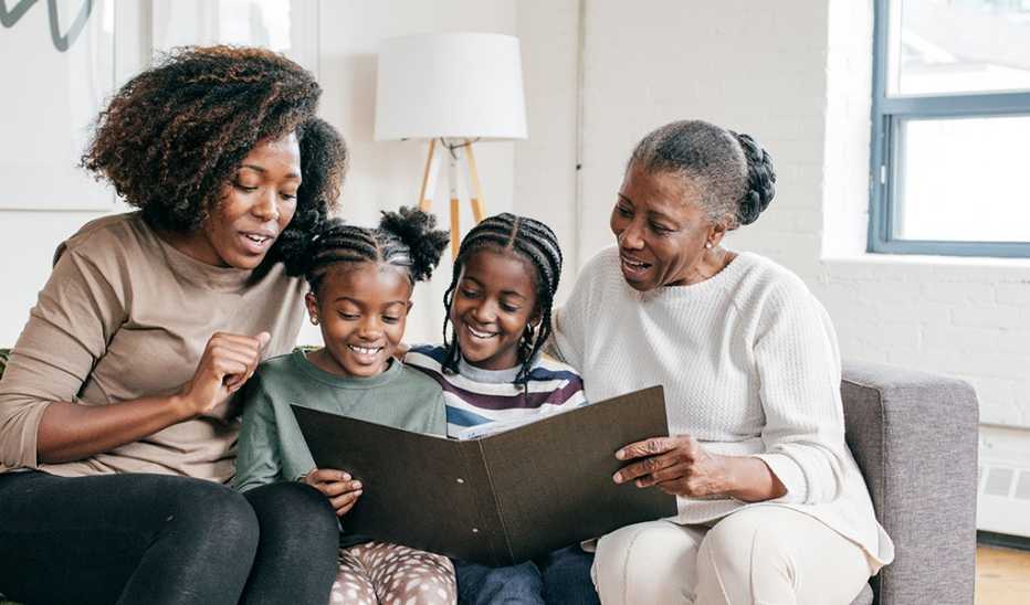 A family of two women and two young children looking at a book together