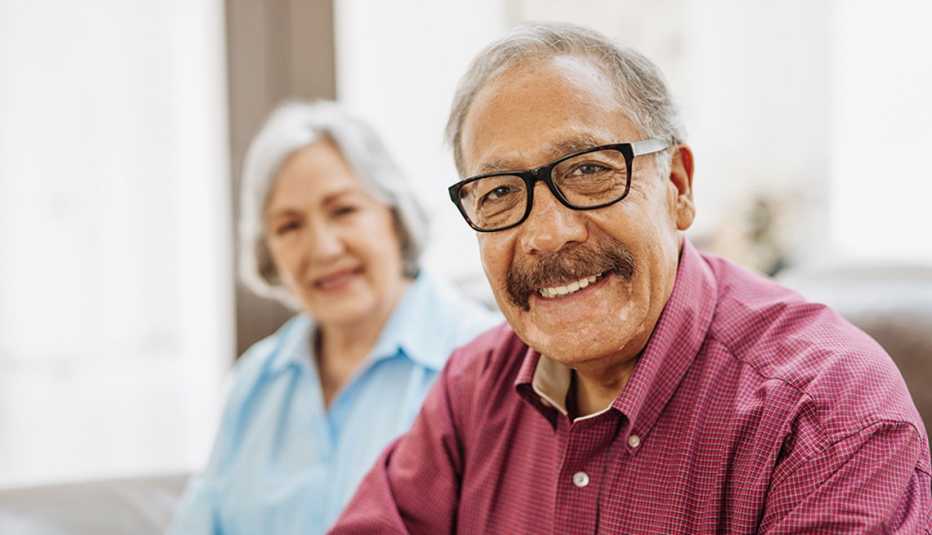 A portrait shot of a man with his wife posing for the photo in the background