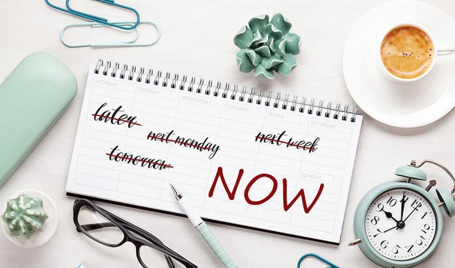 Set yourself up for success by scheduling your most important tasks A notepad and a pen resting on a desk with an alarm clock and coffee beside it