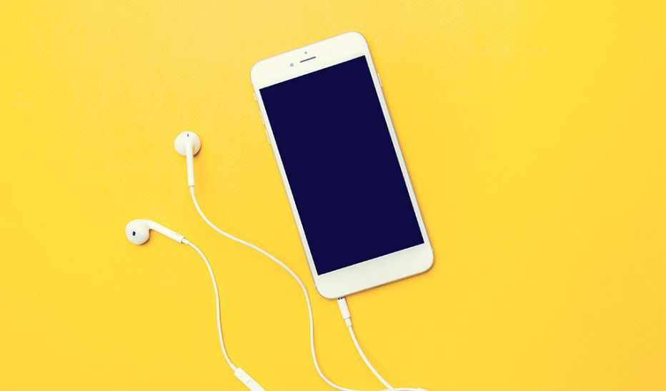 A smartphone with headphones plugged into it on a yellow background