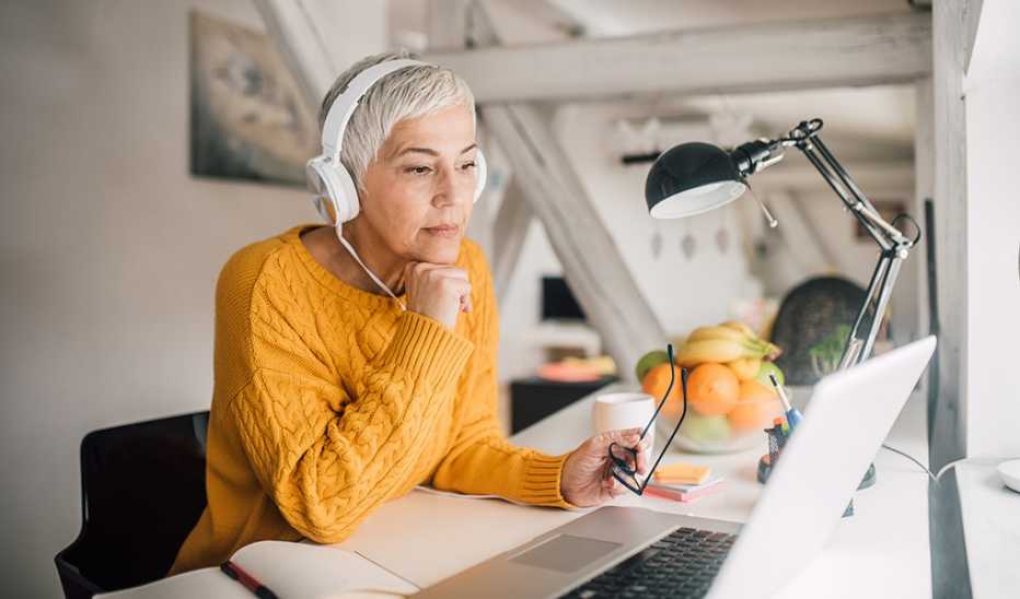 A woman with headphones on lying on a couch