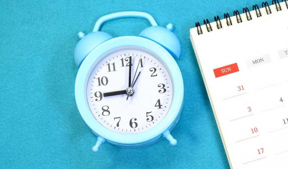 A close-up view of a monthly calendar and clock on a blue background