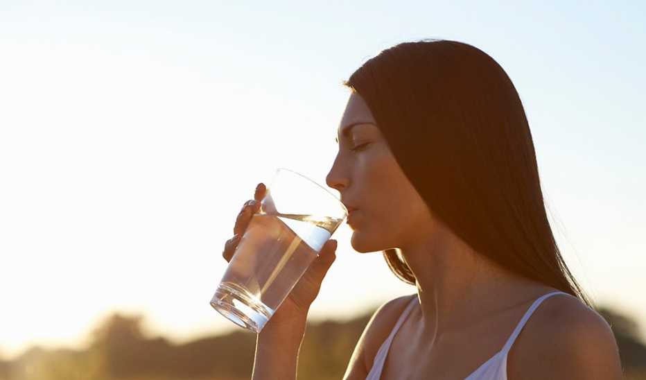 A woman drinking a glass of water outside