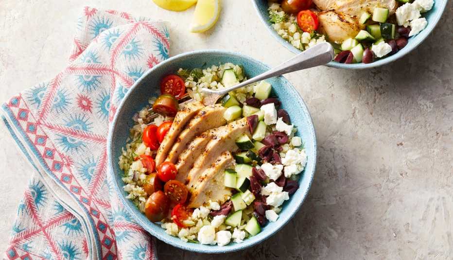 A close-up view of cauliflower rice bowls with grilled chicken in a bowl