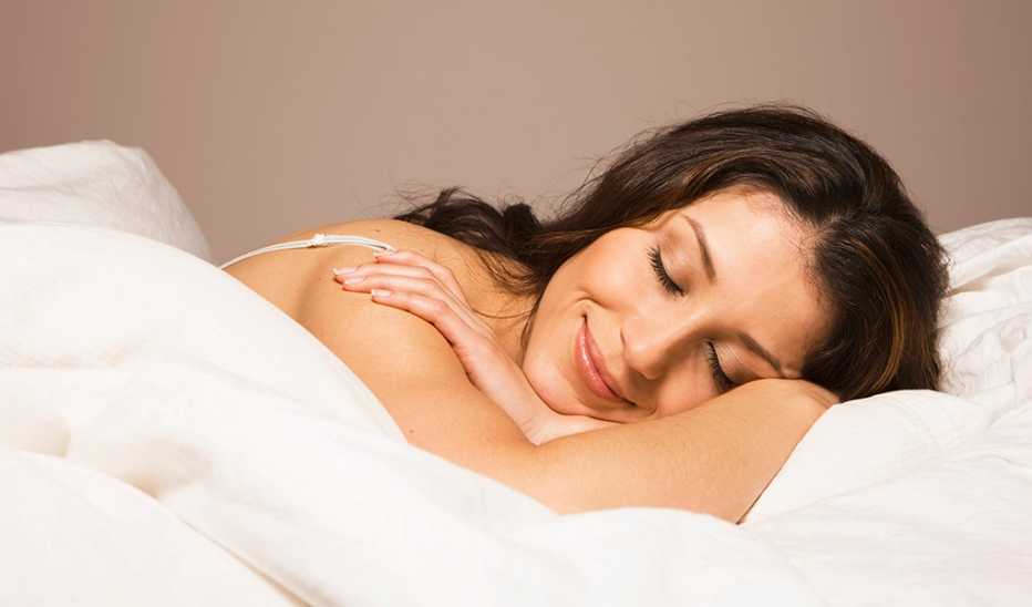 A woman smiling as she sleeps in a bed