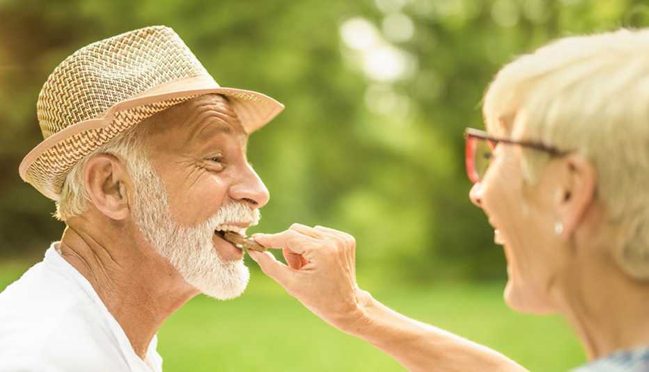 A happy woman putting a piece of chocolate in a man’s mouth