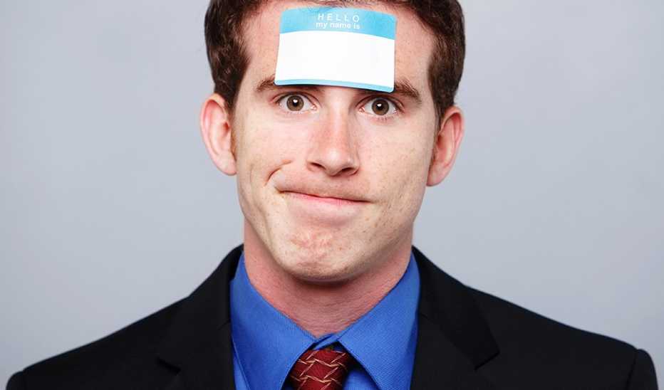 A man in a suit with a "My name is" sticker on his forehead