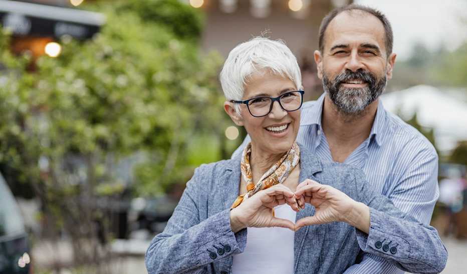 Being kind may lift your spirit A woman making a heart shape with her hands with a man behind her