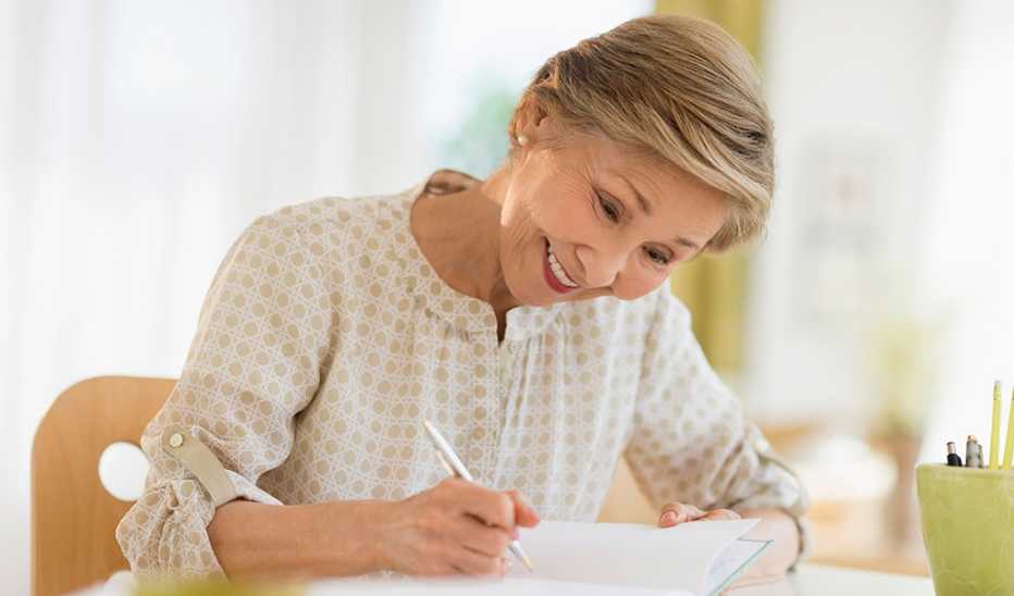 A woman smiling and writing in a journal