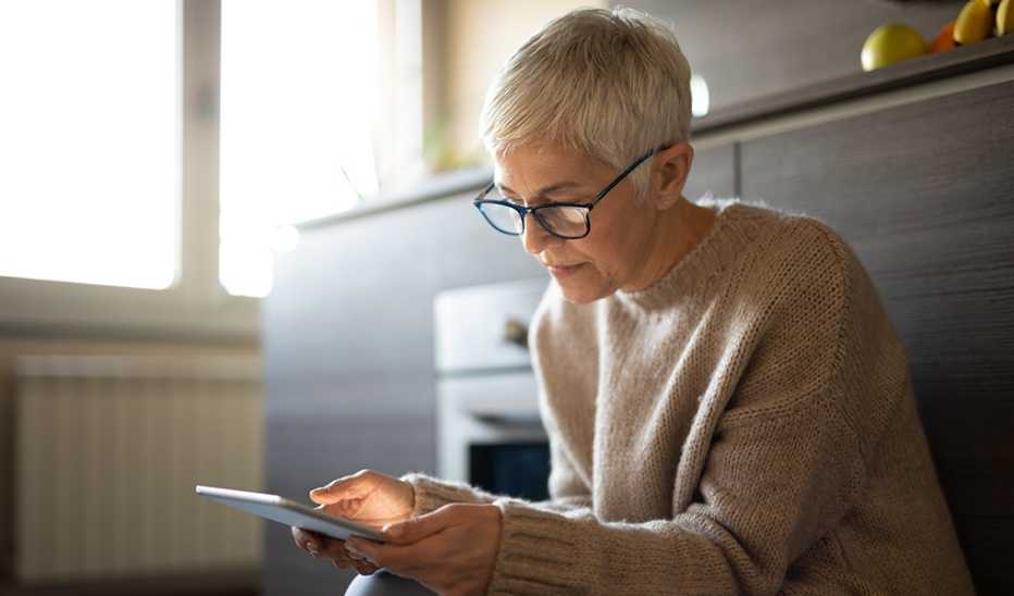 A woman sitting and looking intently at a tablet