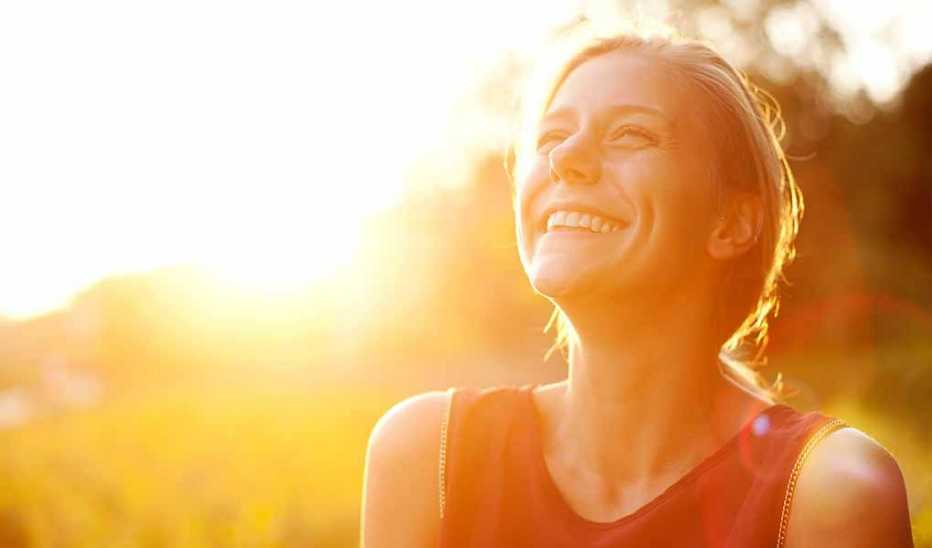 A woman smiling as the sun shines on her