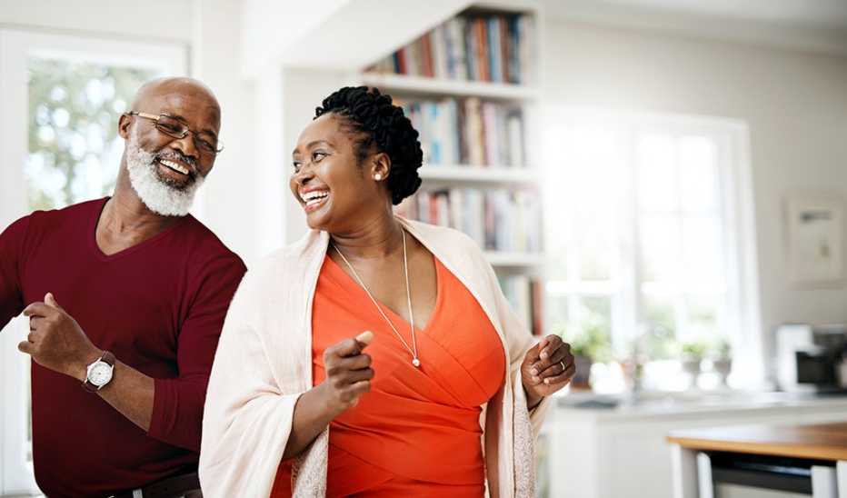 A man and woman smiling and dancing together in a home