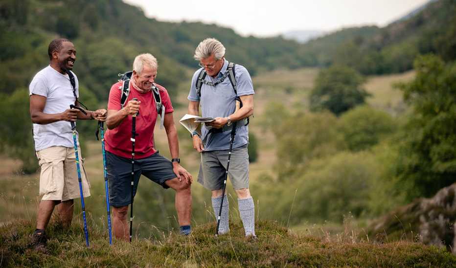 Three men hiking with hiking poles and looking at a map