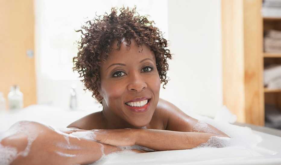 A smiling woman relaxing in a bubble bath