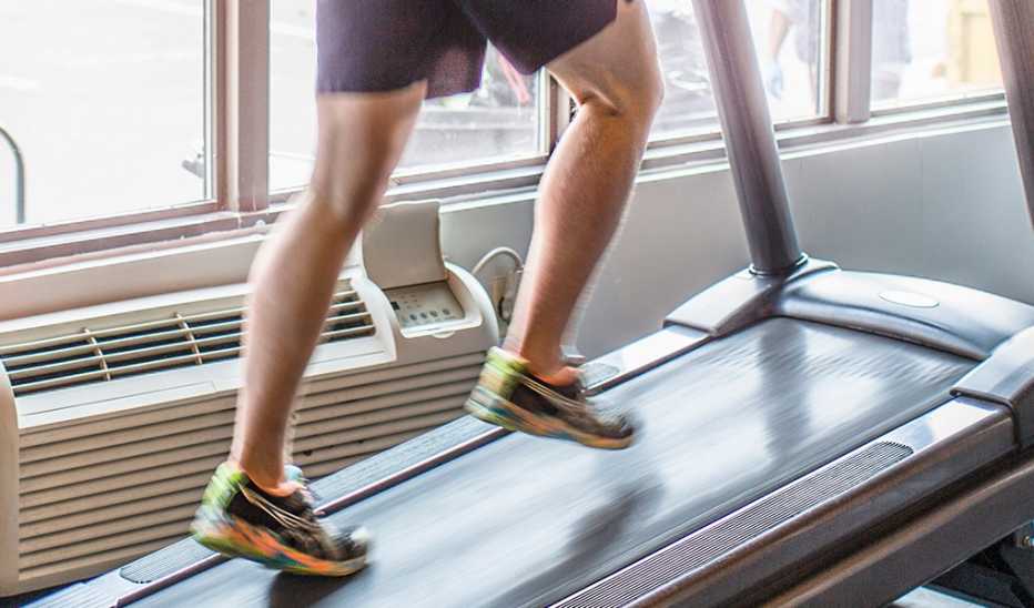 The legs of a man walking at an incline on a treadmill