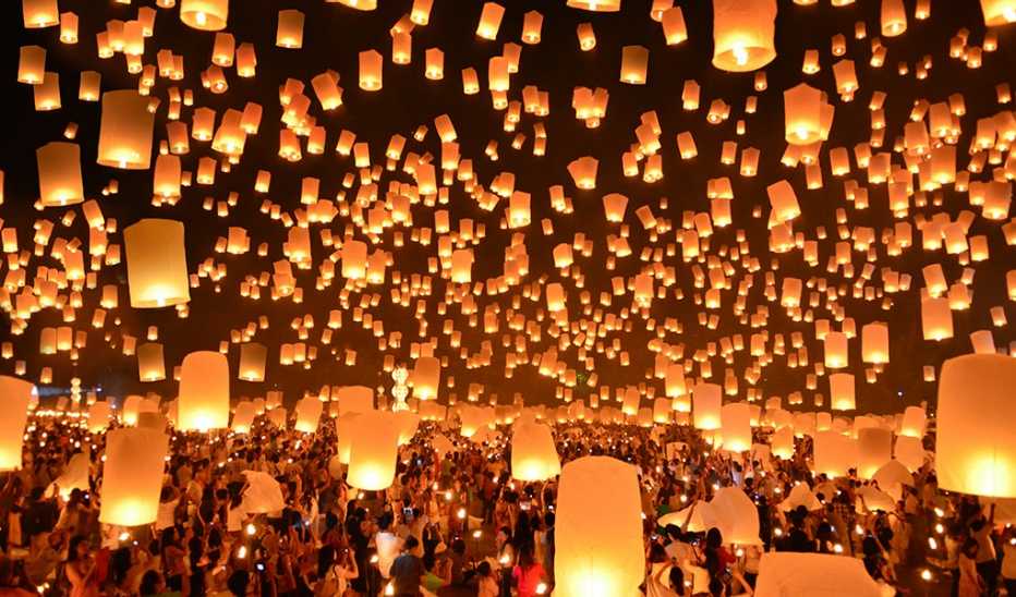 People launching floating lanterns at a Yi Peng festival