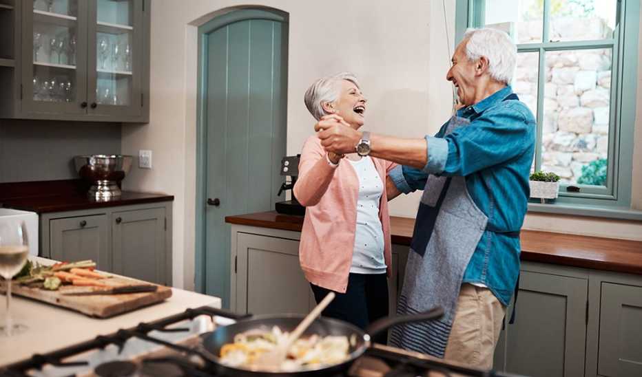 A man and woman dancing together while cooking in a kitchen