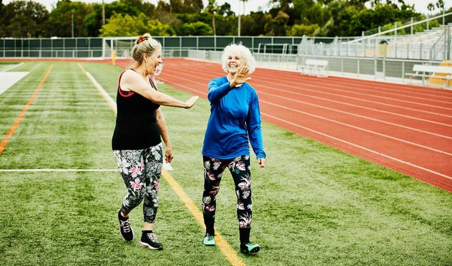 Two women smiling and walking together beside a track