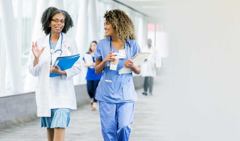 A female doctor and female nurse walking together in a hospital
