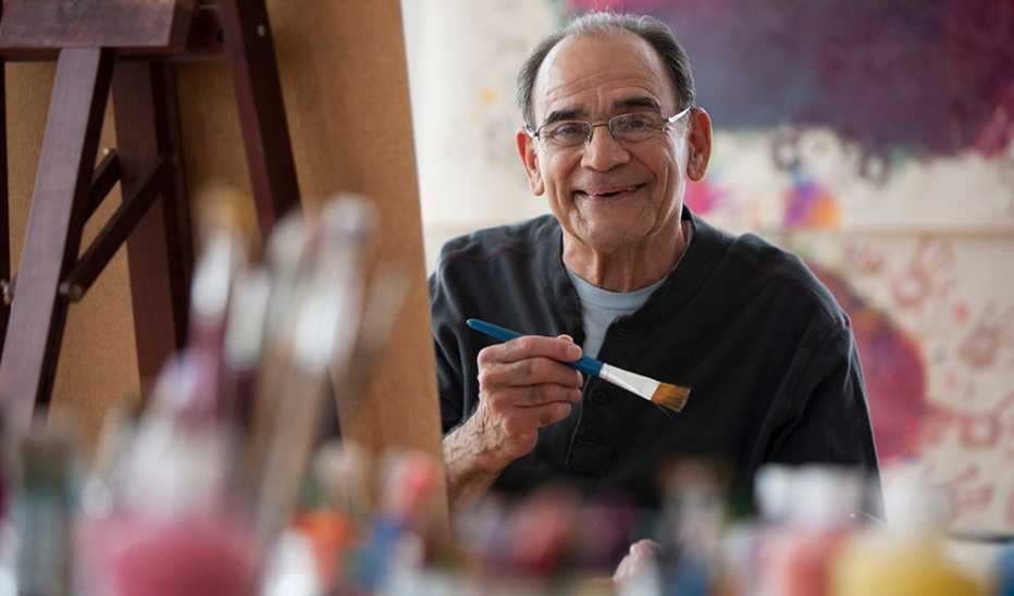 A smiling man painting on an easel