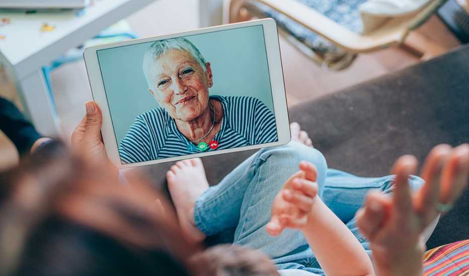 A family having a video call with a woman on their tablet