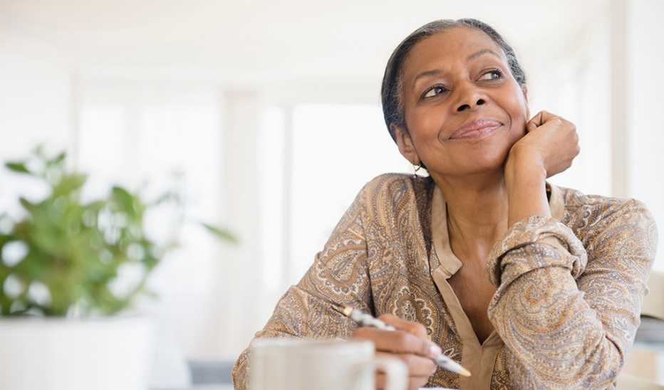 A woman smiling as she writes at a desk