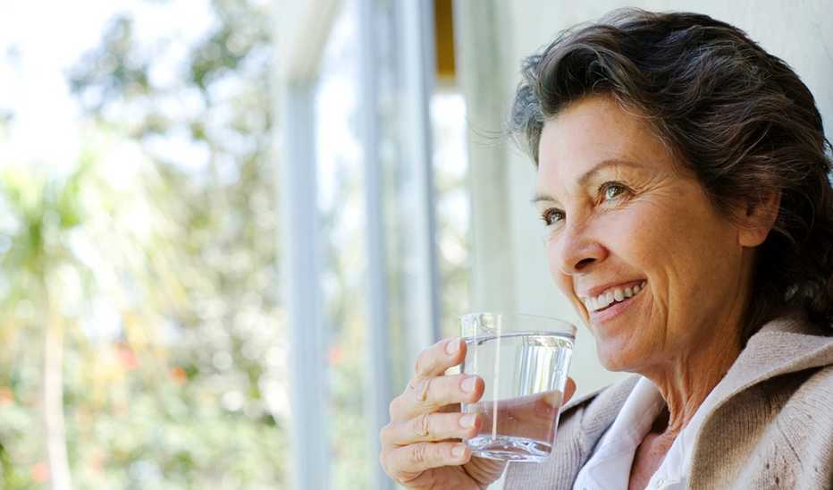 A woman drinking a glass of water by a doorway