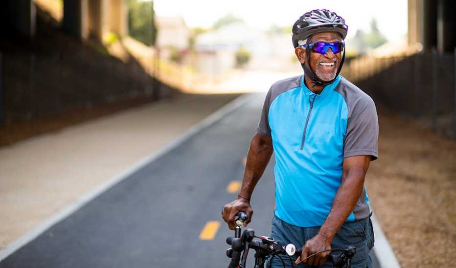 A smiling man on his bicycle on a bike trail