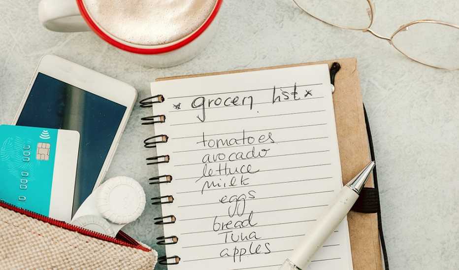 A grocery list written in a notebook laying on a desk