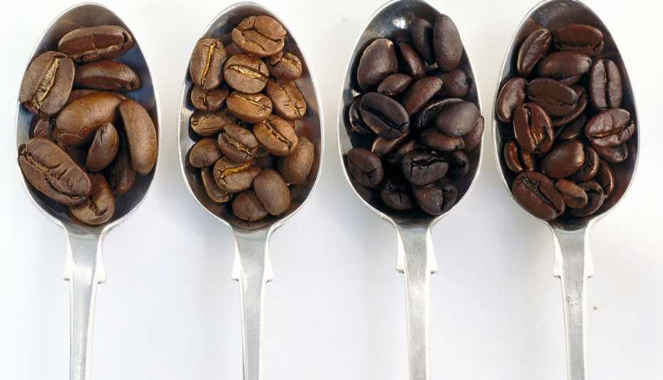 A close-up view of four spoons with different coffee beans