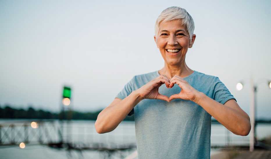 A smiling woman making a heart shape with her hands