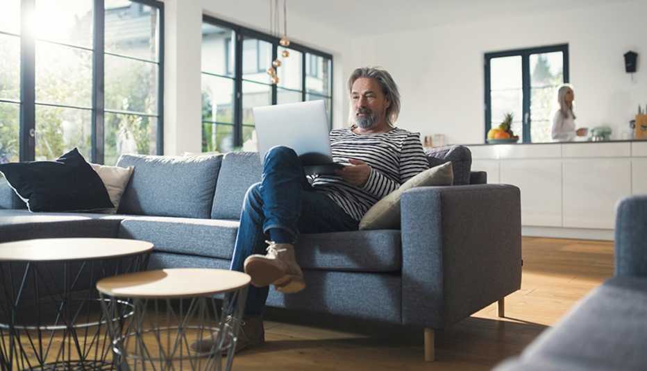 A man sitting on a couch with a laptop on his lap