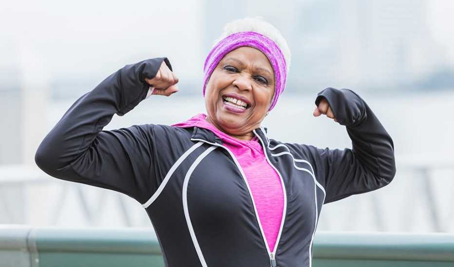 A smiling woman flexing her biceps outside