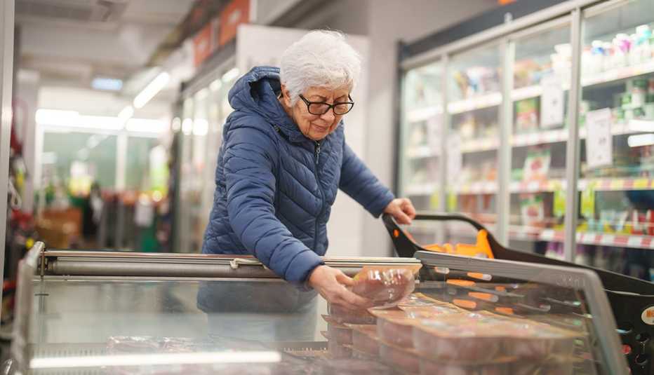 A woman checking the label of a product in a grocery store