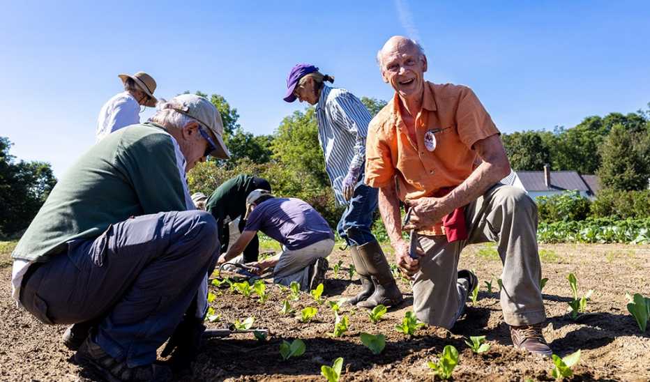Nick Krembs smiling as he gardens on one knee with others