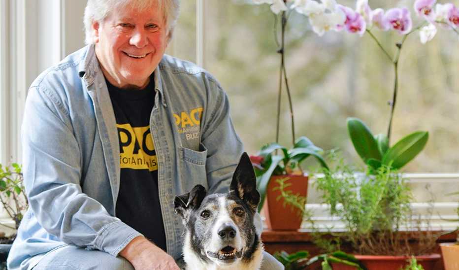 A man, Buzz Miller, smiling in a home with a dog