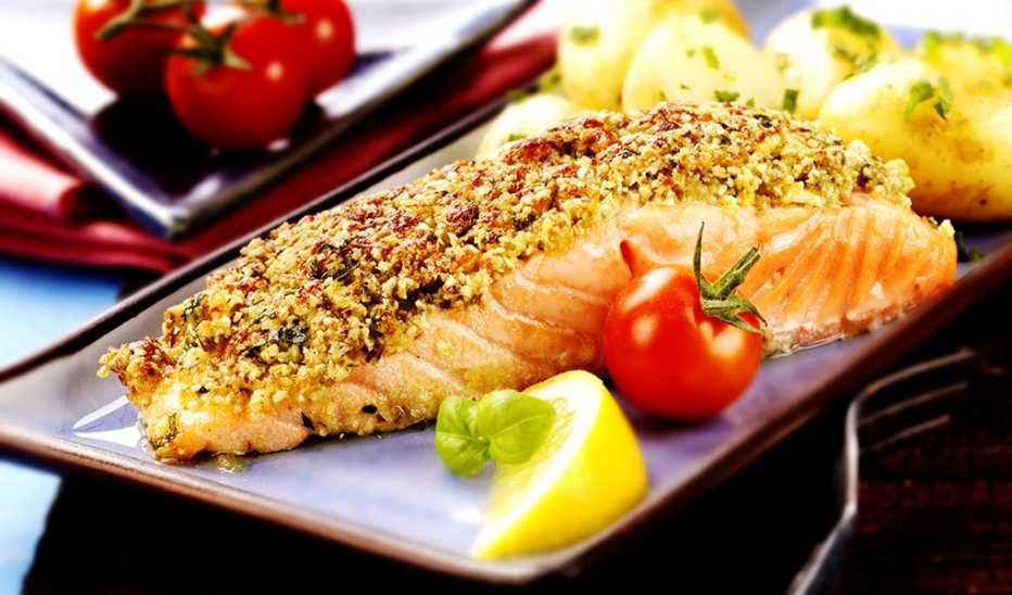 A close-up view of baked salmon with a pesto crust on a plate