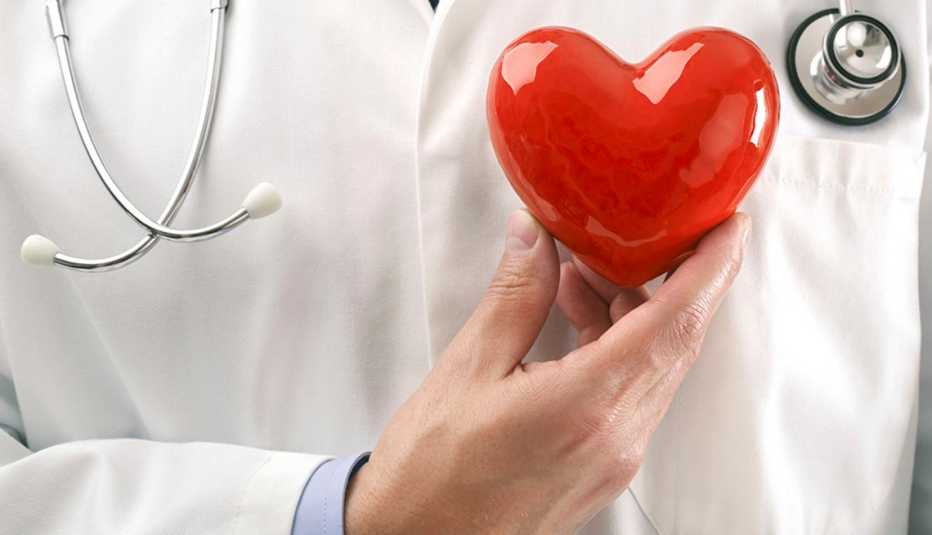 A doctor holding up a heart over their chest