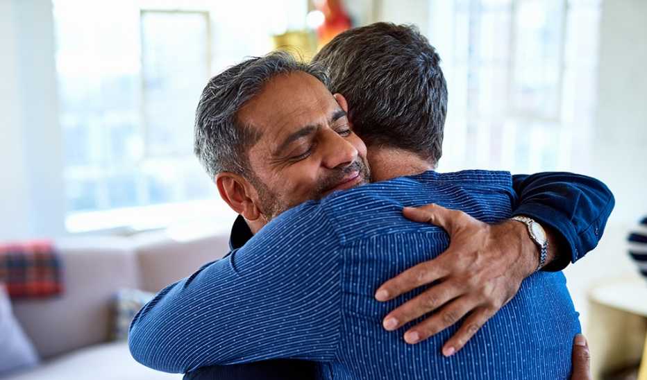 Two men hugging each other inside a home