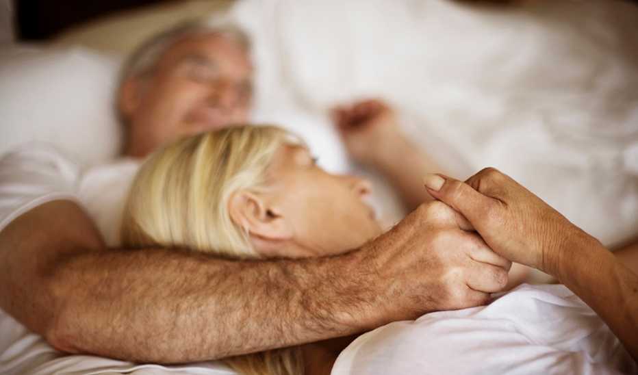 A man and woman cuddling in a bed together