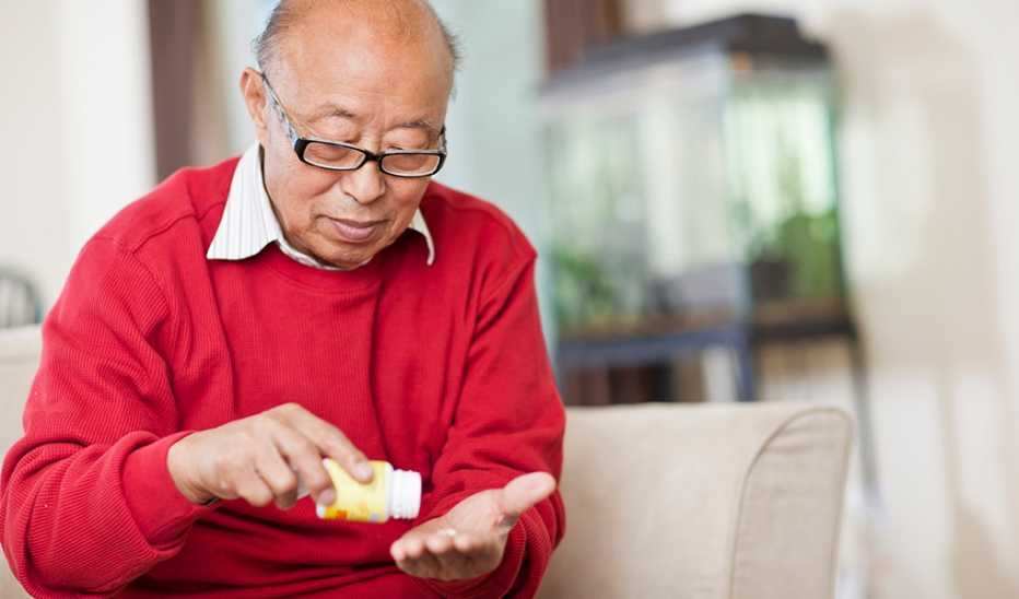 A man pouring a pill from a bottle into his hand