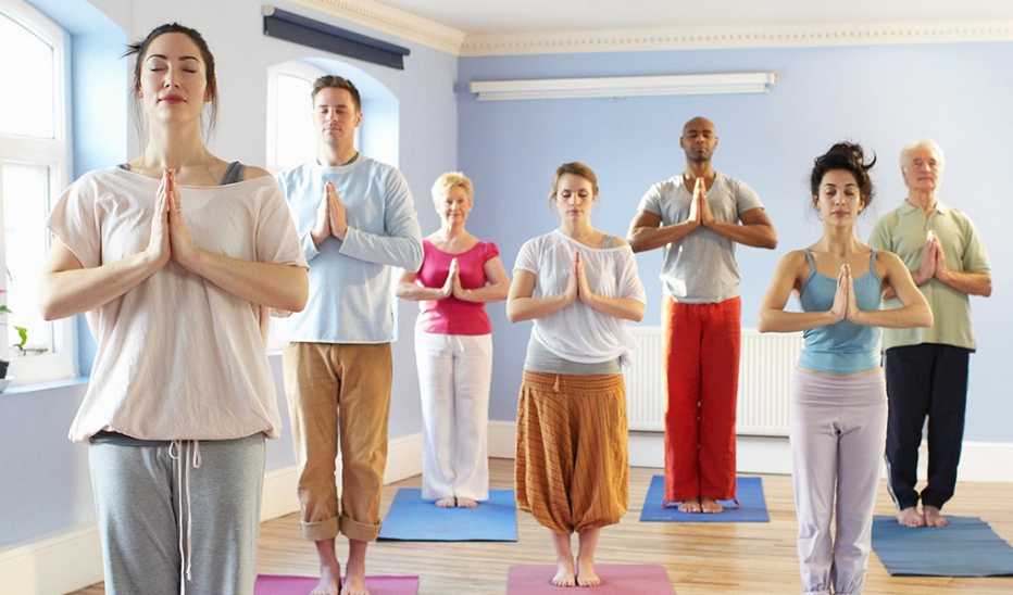 A group of people standing on yoga mats and meditating