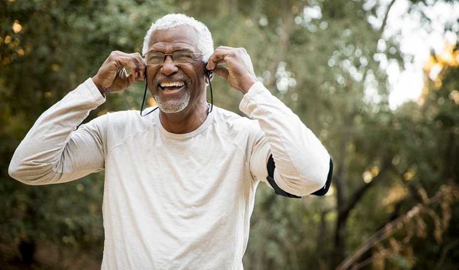 A man puts in headphones while standing outside