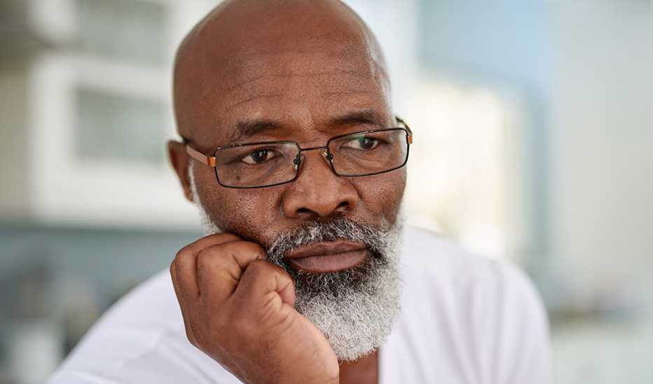 Close up of a man with his hand on his face as he thinks